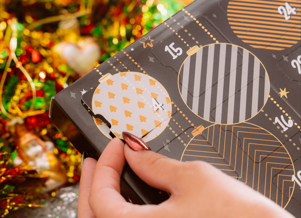 Hand holding a decorative box with geometric patterns against a festive background