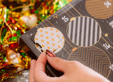 Hand holding a decorative box with geometric patterns against a festive background